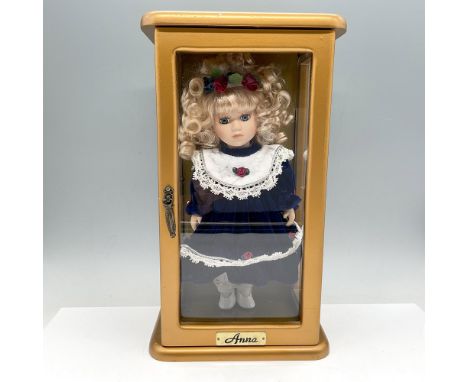 Adorable blonde curly haired doll dressed in blue velvet dress with embroidered accents. Doll comes in glass and wood display