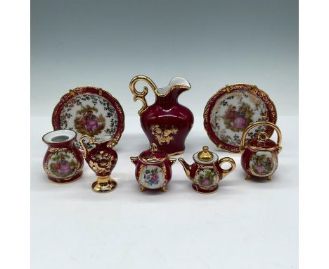 Decorative pieces in burgundy porcelain adorned with hand painted scenes and gilt accents. Collection includes 2 plates; pitc