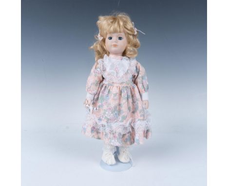 Hand painted porcelain doll dressed in period hand sewn dress, pantaloons and shoes carrying an ornament. Metal stand include