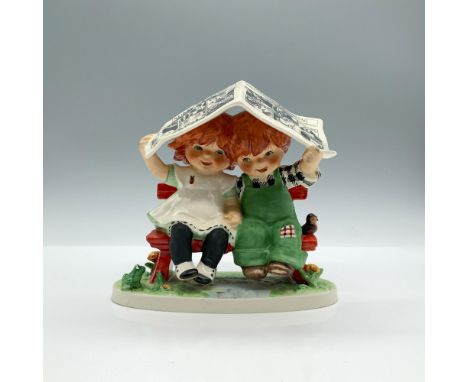 A hand painted figure portraying two kids covering themselves from the rain with a newspaper. Goebel backstamp. Charlot Byj i