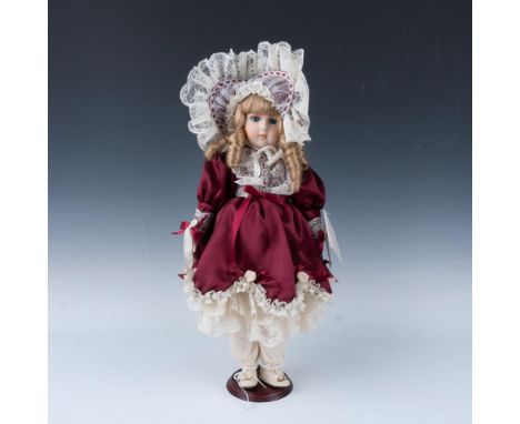 Doll is hand crafted of bisque porcelain and hand painted with soft features. Dress and hat are hand sewn purple satin with l