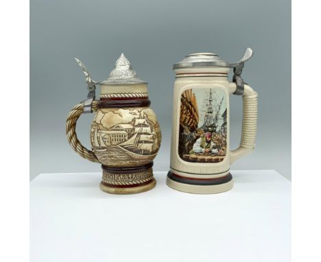 A set of 2 beer steins, a white one with a wooden texture showcasing a painting of men crafting sailing ships, and a round be