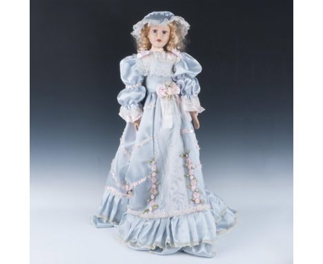 This limited edition, fine bisque porcelain doll is hand painted with hand sewn period dress and matching hat. Satin and lace