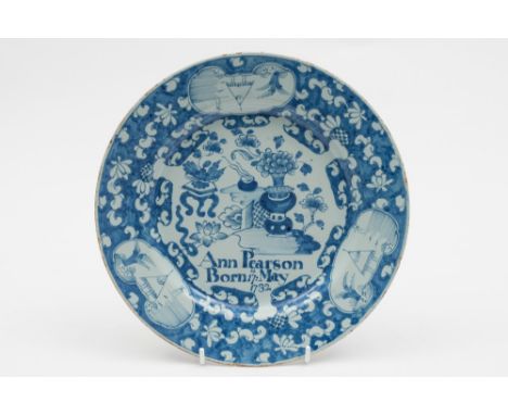 An English dated delftware plate: painted in blue with a Chinese vase of flowers and a flower table by a trellis fence and in