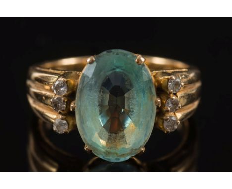 An aquamarine and diamond ring:, the central, oval aquamarine approximately 14mm long x 10mm wide, between circular diamond t