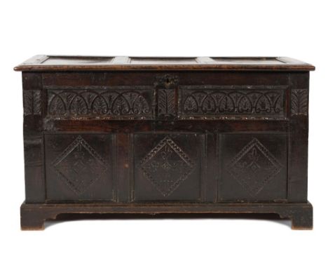 An antique oak rectangular coffer:, with a plain triple moulded panel hinged top, the front with twin carved foliate and scro