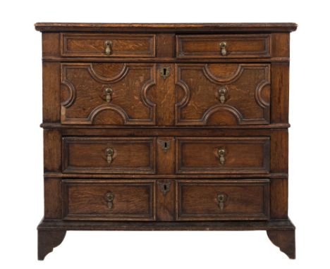 A Jacobean oak rectangular chest:, in two parts, containing two short and three long moulded and geometric panel drawers, on 
