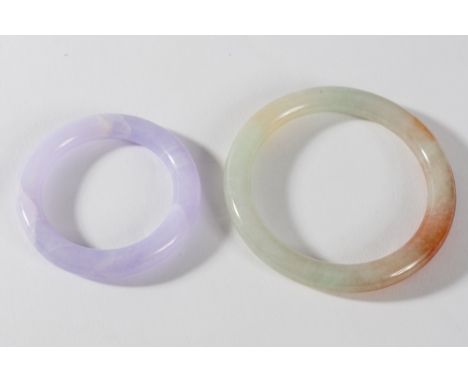 A Chinese lavender jadeite small bangle or ring and a celadon and russet jadeite bangle: the first 7cm diameter, the second 8