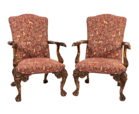 A pair of carved mahogany library armchairs in the 18th Century Irish taste:, with arched upholstered stuffover backs and sea