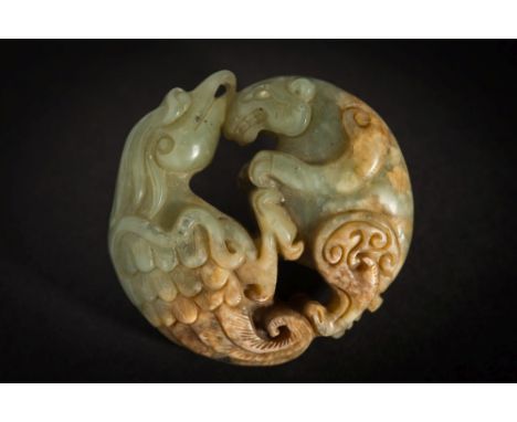 A carved celadon and russet jade pendant: of circular form, depicting a bird and animal fighting, 5.3cm. wide.
