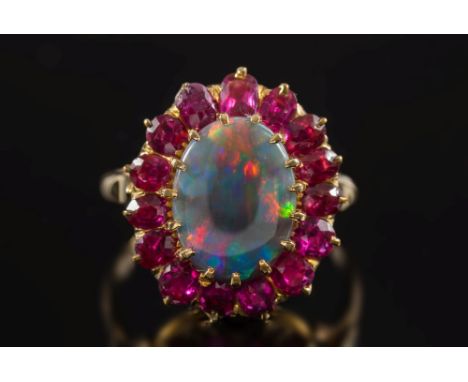 A black opal and ruby oval cluster ring: with central oval black opal approximately 13mm x 10mm claw-set within a surround of