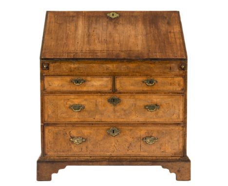 An early 18th century cross and feather banded walnut bureau:, the sloping fall enclosing a fitted interior with graduated dr