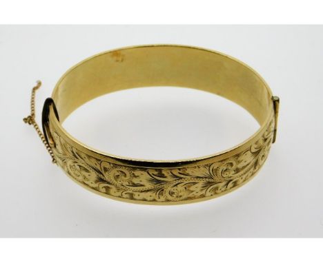 A 9ct gold metal core bangle, safety chain a/f, internal measurement 60.5mm at widest. 42.9g inclusive