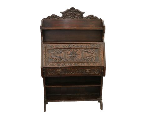 Jacobean style heavily carved oak bureau having a scroll carved top rail above a shelf, the sloped front opening to reveal a 