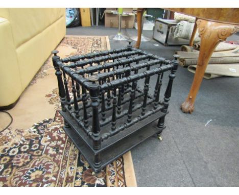 An ebonised four division canterbury with turned design and under-tier on ceramic castors