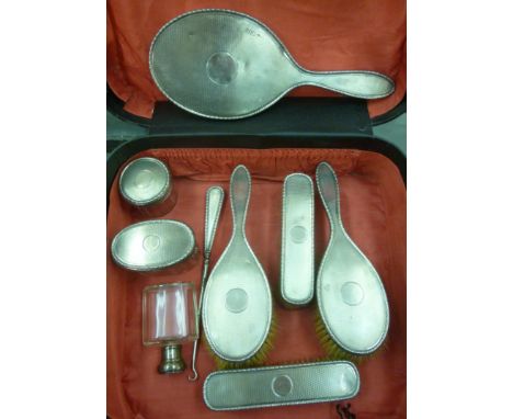 A matched nine piece silver backed dressing table set, viz. four brushes, three jars, a hand mirror and crochet hook, each ha