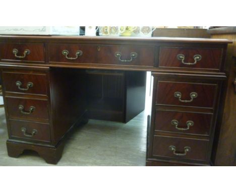 A modern mahogany finished, nine drawer, twin pedestal desk with a green faux hide scriber, raised on bracket feet  30''h  48