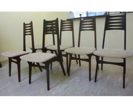 A set of six 1970s teak framed, designer dining chairs, each having a stylised ladder back and an upholstered seat pad, raise