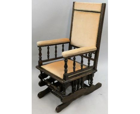 An American stained beech rocking chair, with turned bobbin supports, beige upholstery.