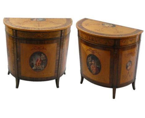 A pair of George III style satinwood and polychrome painted D shape commodes, the top with a band of scrolling foliage and an