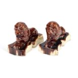 A PAIR OF VICTORIAN TREACLE-GLAZED POTTERY MODELS OF RECUMBENT LIONS