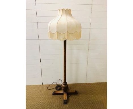 A large wooden floor lamp in the arts and crafts style with a fringed lamp shade 