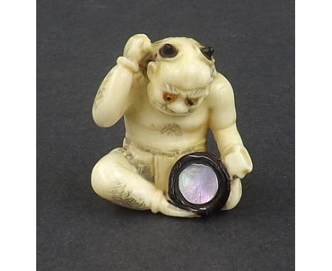 Japanese stained ivory netsuke modelled as a seated oni with drum, mother of pearl inlay, signed inset tablet, 1.5" high 