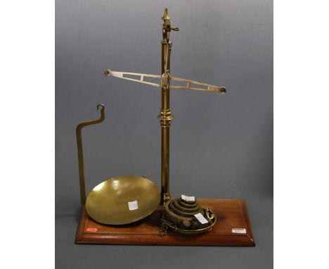 A set of early 20th century brass beam scales with weights, on a mahogany plinth base