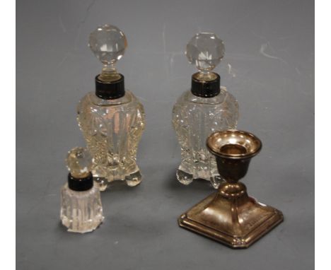 A George V silver dwarf table candlestick; together with three cut glass scent bottle sand stoppers, each with silver collar 