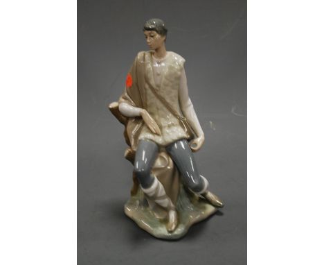 A large Lladro porcelain figure of a young man seated on a treestump, having printed mark verso, h.27cm