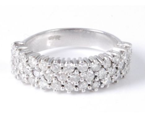 A contemporary white metal and diamond half eternity ring, arranged as three rows of claw set small brilliants, the band stam