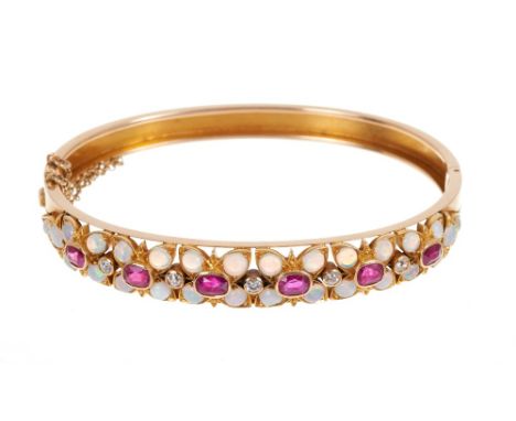 Late Victorian opal, ruby and diamond hinged bangle, the wide graduated gold bangle with six stylized flower head clusters, e