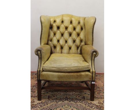 Georgian style leather upholstered wing armchair, with button close-stud green leather upholstery on square channel carved le