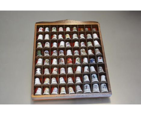 A wall display stand containing a collection of sixty nine ceramic and three metal thimbles (25cm x 36cm)