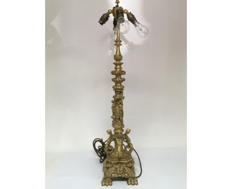 A Quality gilt metal lamp the tall column with raised masks and folate scrolls, later converted to electric sold with a white