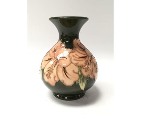 A petite green Moorcroft vase decorated with Hibiscus flowers.  Measures approx 13cm tall.