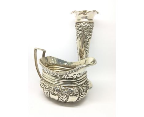 An ornately decorated silver jug, hallmarked for London, maker possibly Josiah Williams &amp; Co, alongside a silver stem vas