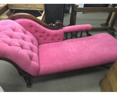 A Victorian mahogany chaise longue with pink button upholstery on turned legs brass caps and casters