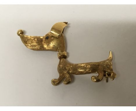 A Quality 18carat gold brooch in the form of a dog with reversing head and ruby and sapphire eyes weight 5.5g length 3.5cm