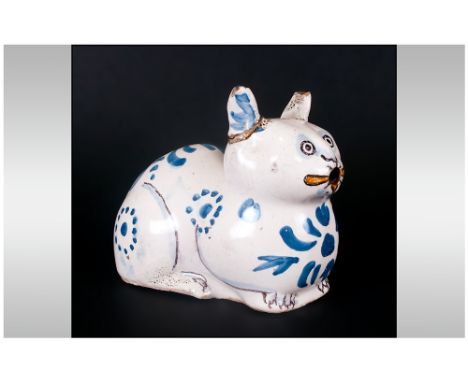 Rare Antique Delftware Cat Of Unusual Reclining Form decorated in blue hues and yellow highlights to the mouth. Paws defined 