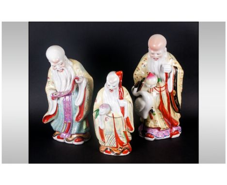 Three Chinese Famile Rose Porcelain Decorated Figures Of Three Wise Man Or Sages, one reading a scroll, another with a heron 