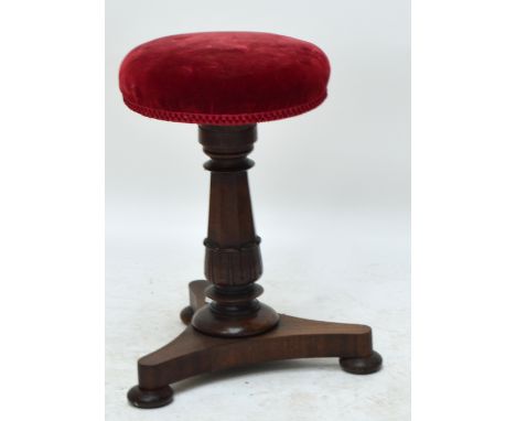 A mahogany circular piano stool on ring turned and carved column to tripartite base with flat bun feet, with upholstered seat