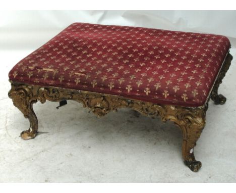 A large 19th century giltwood stool with upholstered padded seat and C foliate scroll frame on mask cap scrolling supports. C