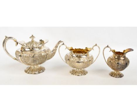 An Edwardian hallmarked silver embossed three piece tea service with gilt wash interior and foliate C-scroll decoration throu