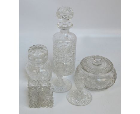 A group of clear cut glass items comprising a cylindrical decanter, a squat jar and cover, a further example, a pair of candl