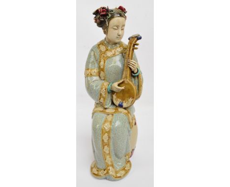 A c.1930s Chinese ceramic figure of a seated woman playing ruan, her robes with turquoise painted crackle glaze and with flor