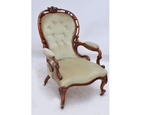 A Victorian walnut spoon back chair, the detailed carved and pierced frame with button upholstered back, padded arms, and ser