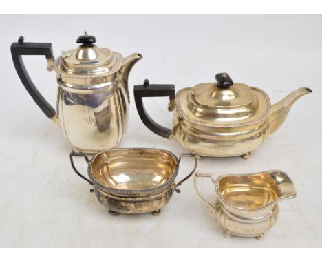 A George V hallmarked silver four piece tea set comprising a teapot of oval form with fluted corners, angled handle, raised o