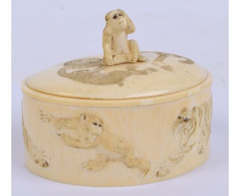 A Japanese Meiji period ivory tusk trinket box, the sides decorated with two scenes with a tiger and a monkey, the top of the