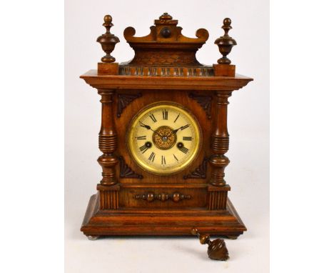 A c.1900 German walnut cased fourteen day mantel clock with turned finials above circular dial set with Roman numerals flanke